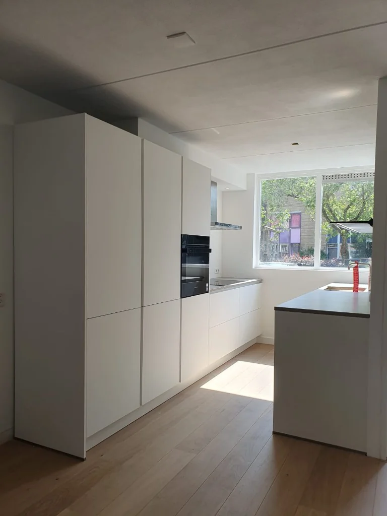 Lichte moderne keuken met hoge kasten en houten vloer